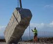 Large stone being raised by crane